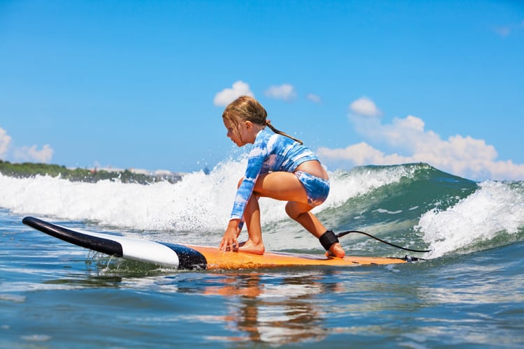 young girl surfing at one of the best all-inclusive family resorts in the us