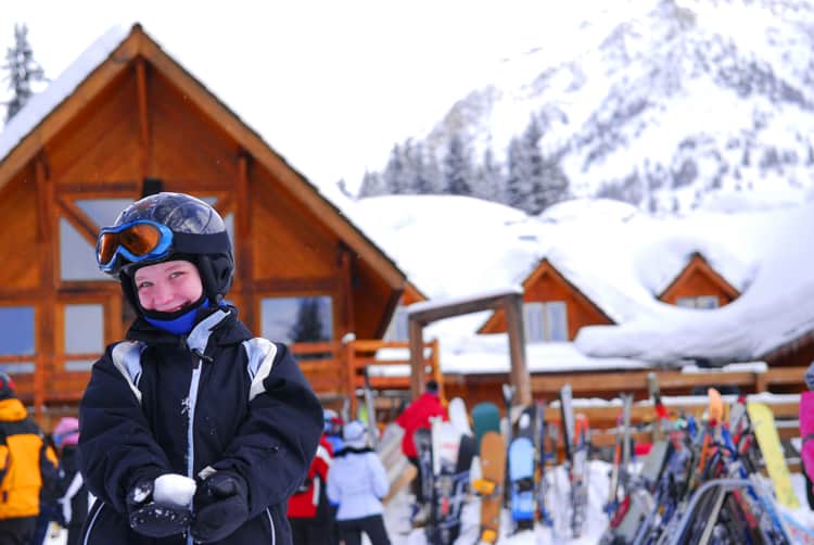 boy with snowball in front of ski lodge at one of the best all-inclusive family resorts in the us
