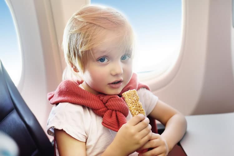 child in an airplane eating a granola bar for an easy travel snack