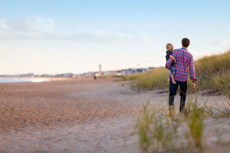 father and child walking on beach