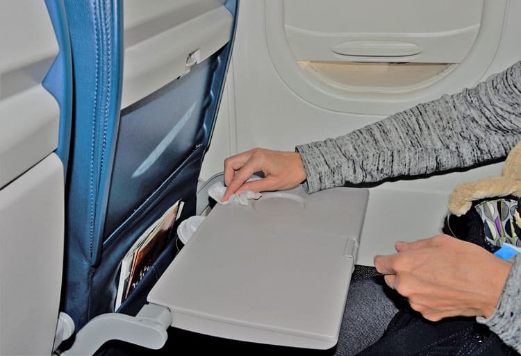 20 Coronavirus Travel Tips to Keep Your Family Safe 17 someone wiping down airplane tray table