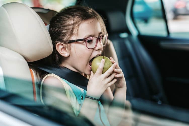 20 Coronavirus Travel Tips to Keep Your Family Safe 12 girl eating apple in car
