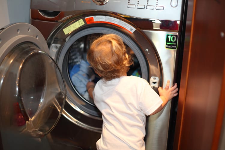 What To Clean When Your Child Is Sick 5 Child Reaching Into The Washing Machine