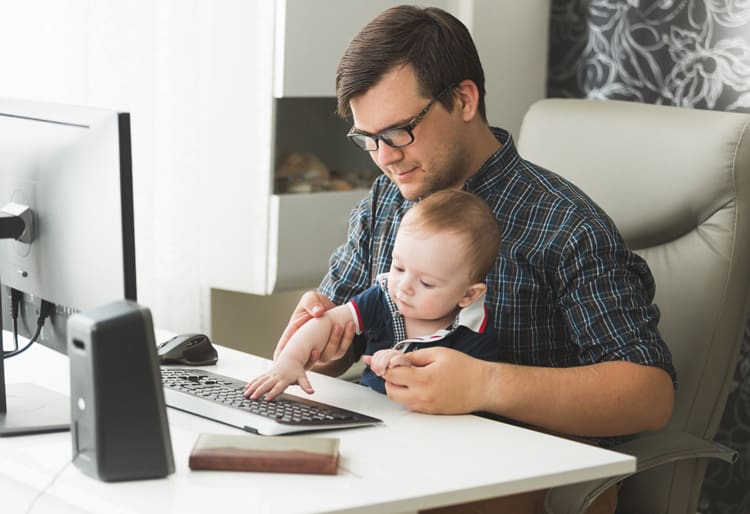 dad working on computer with child in lap