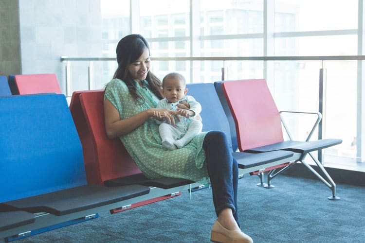 Flying With a Newborn: 10 Ways to Make it Easier 8 mother sitting in airport with infant