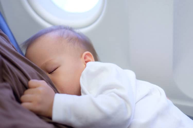 Flying With a Newborn: 10 Ways to Make it Easier 5 baby nursing in an airplane