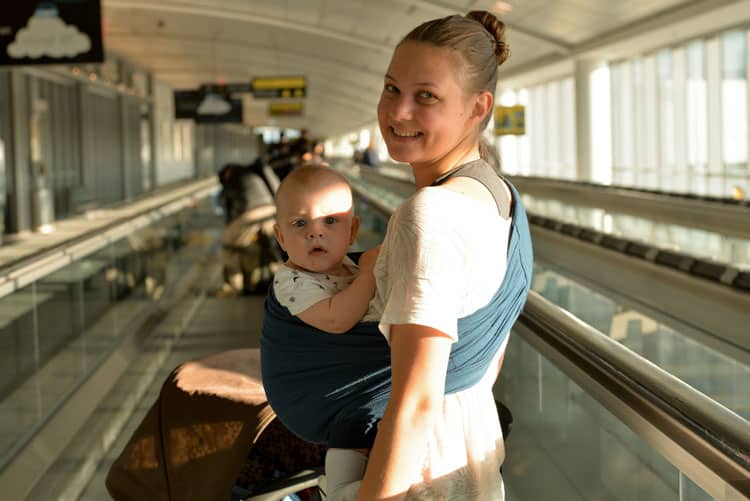 Flying With a Newborn: 10 Ways to Make it Easier 6 woman in airport with baby in a carrier