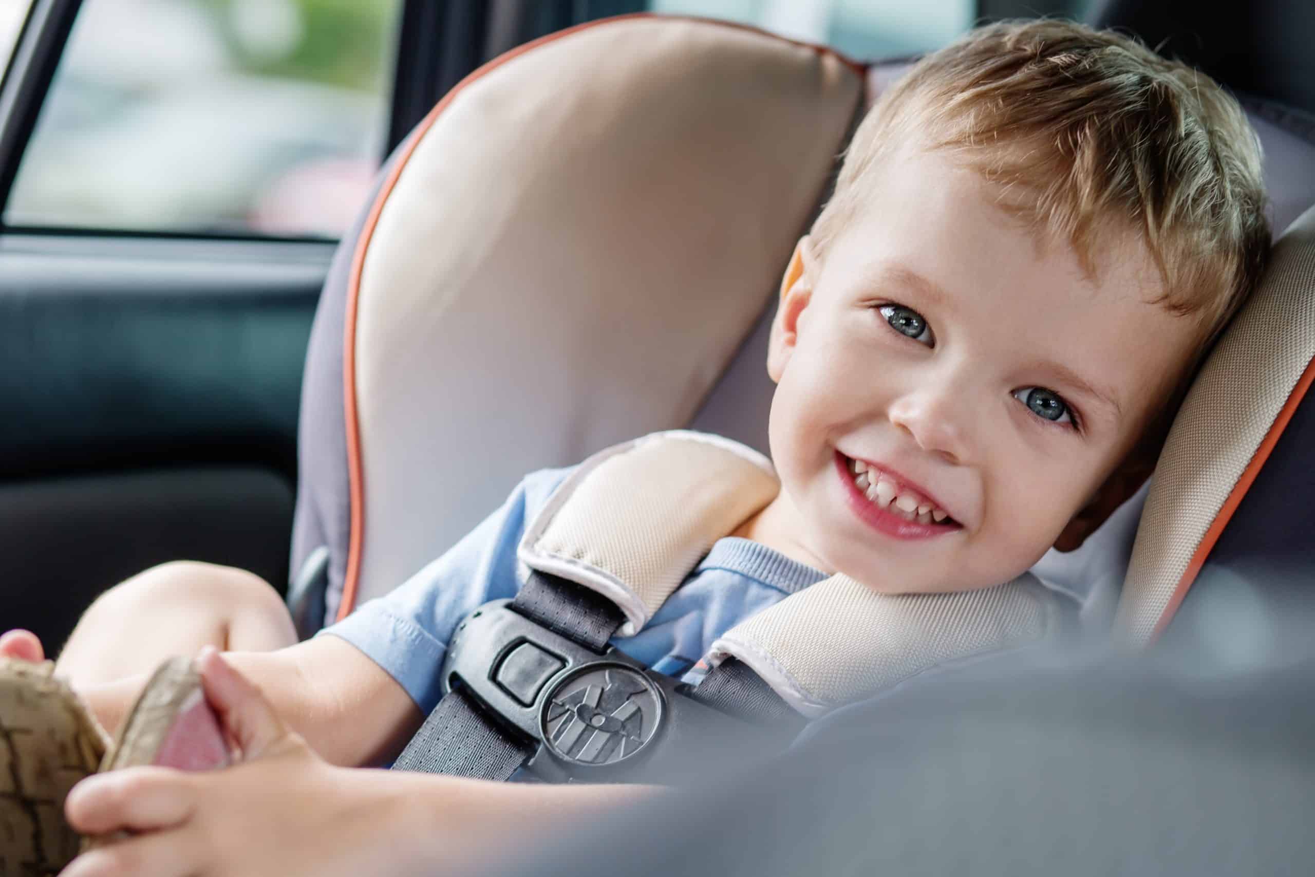 Happy young boy securely fastened in a car seat during travel.