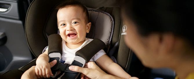 Child secured in baby car seat for safe travel during a road trip.