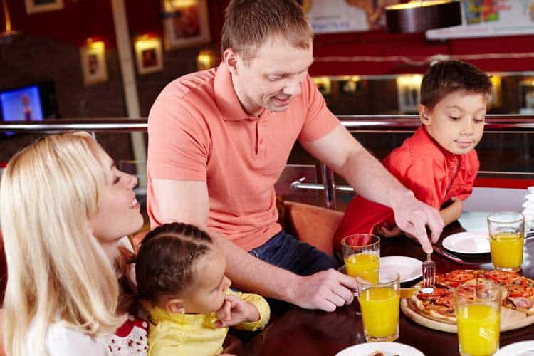 Family dining with children at a kid-friendly restaurant, pizza, and beverages.