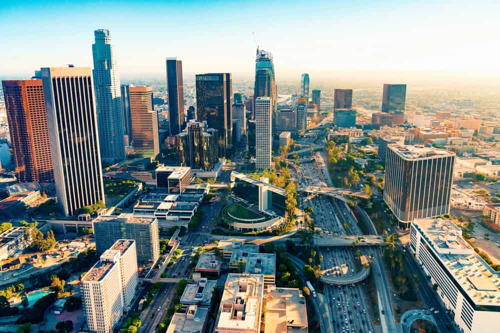 Aerial view of Los Angeles cityscape featuring tall buildings and busy highways.