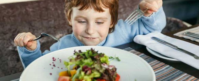 Child Enjoying A Healthy Toddler Lunch With Fresh Vegetables.