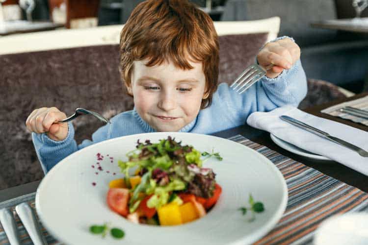 Child enjoying a healthy toddler lunch with fresh vegetables.