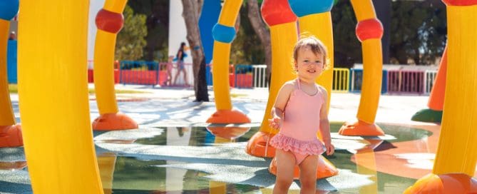 Child enjoying water play at colorful splash pad near Sesame Place.