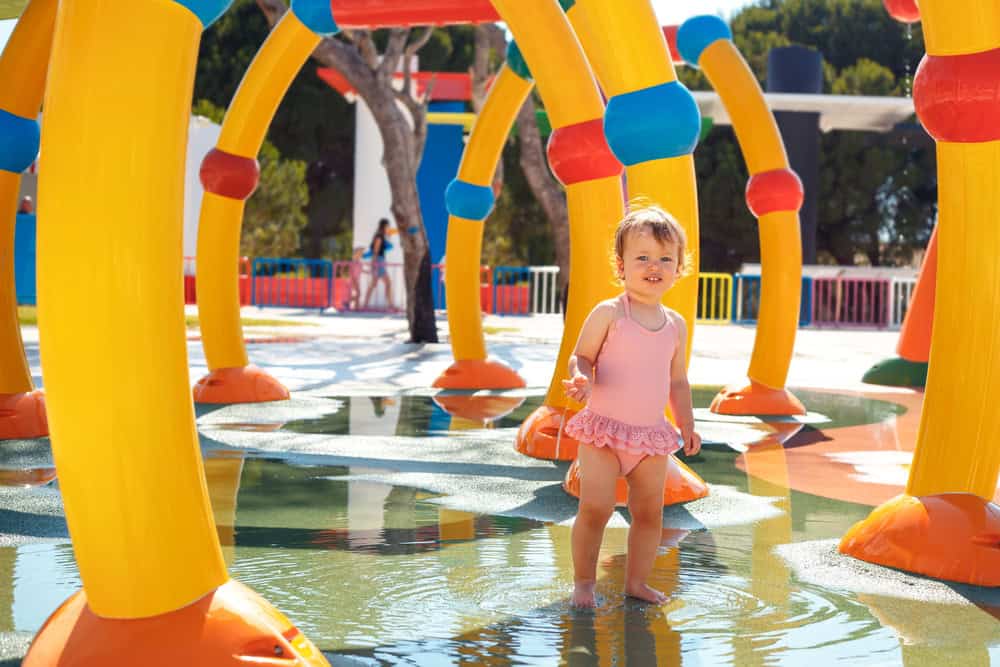 Child enjoying water play at colorful splash pad near Sesame Place.