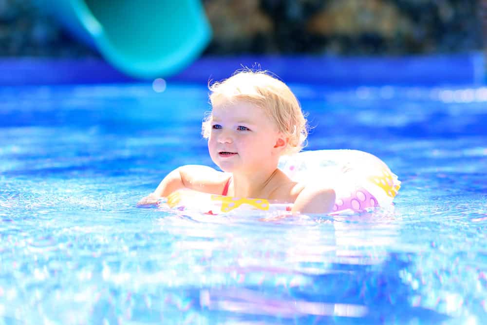 Child enjoying a swim in the pool with a floatation ring for safety.