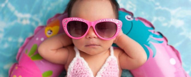Baby In Pink Sunglasses And Swim Diaper Relaxing In Pool Float.