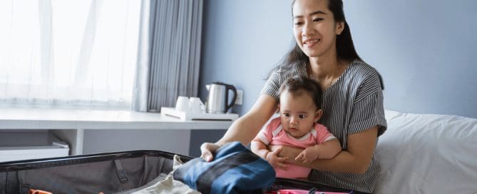Packing And Organizing Baby Gear In A Suitcase For Travel With A Smiling Mother And Her Baby.