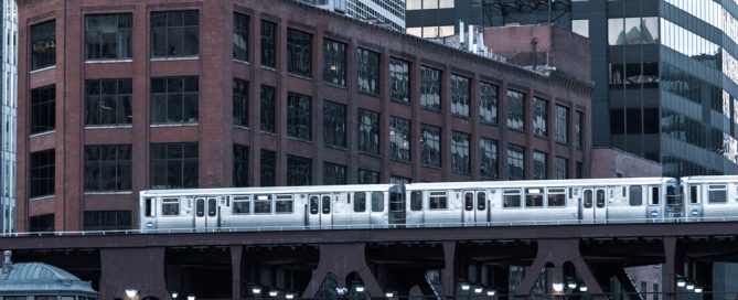 Elevated Train Passing Through Downtown Chicago With City Buildings In Background.