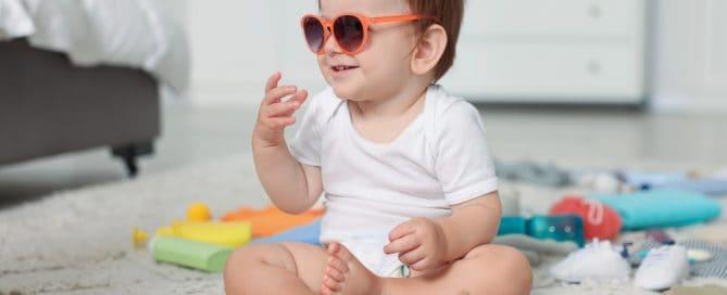 Cute Toddler Wearing Sunglasses Playing With Toys On The Floor.