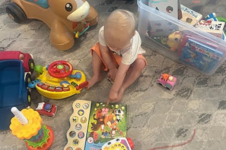 Child playing with colorful toys on a carpeted floor.