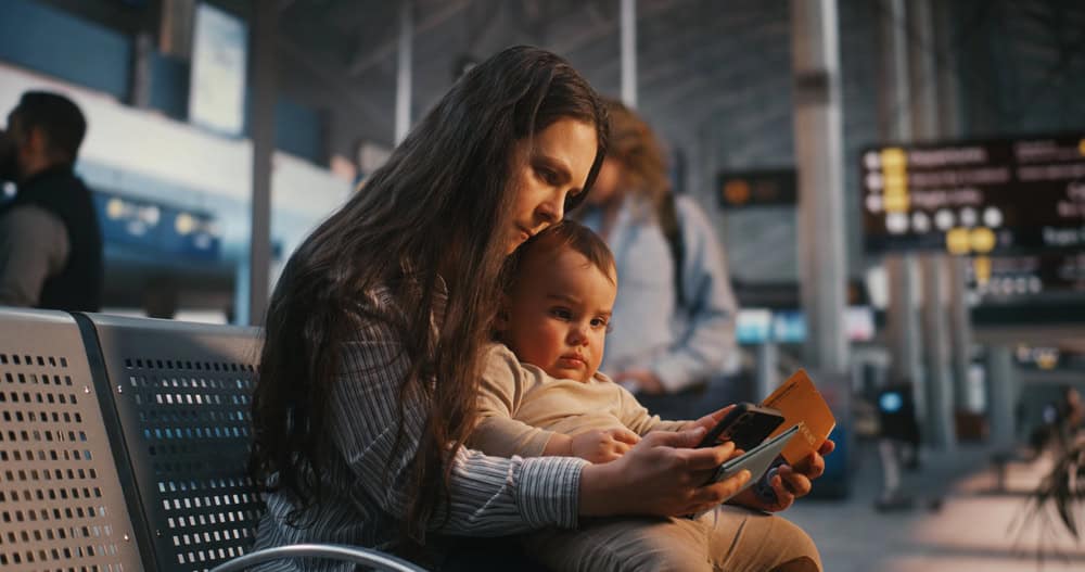 Mother and child using a smartphone at an airport terminal.