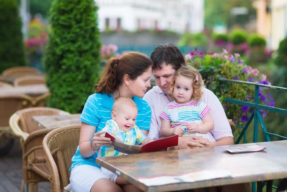 Family enjoying outdoor meal at a restaurant with children and parents.