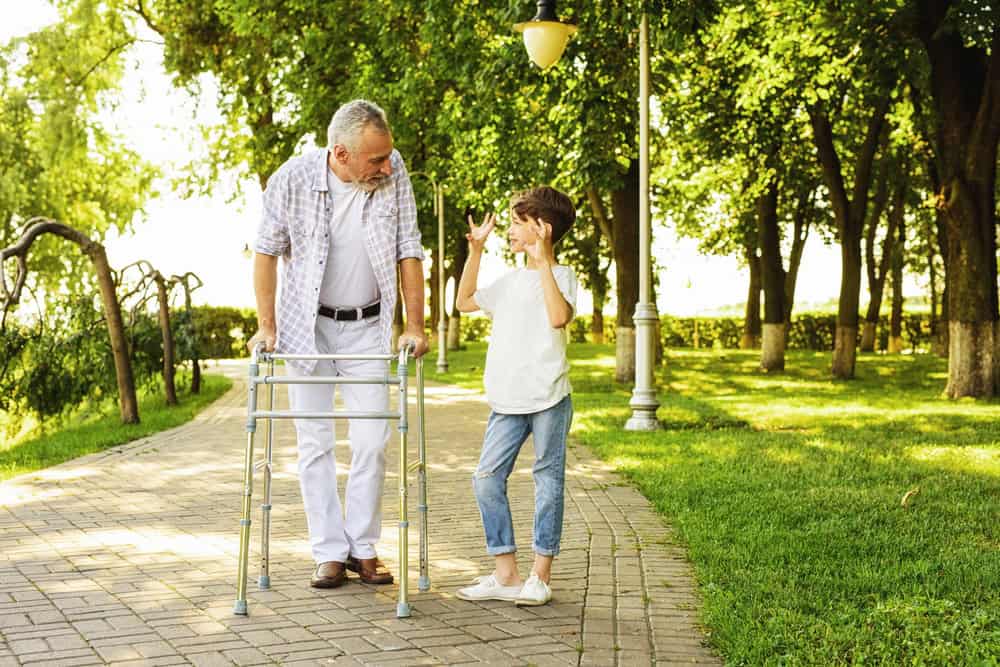 Child using hearing aids with grandfather in park during daytime.