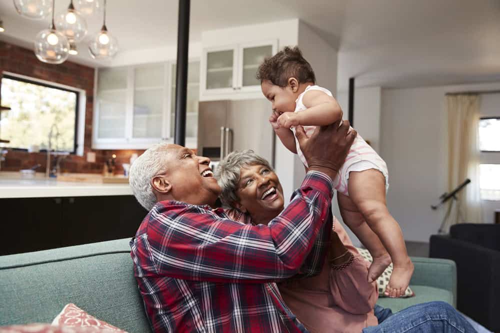 Grandparents playing with a young child at home, smiling and enjoying quality time.