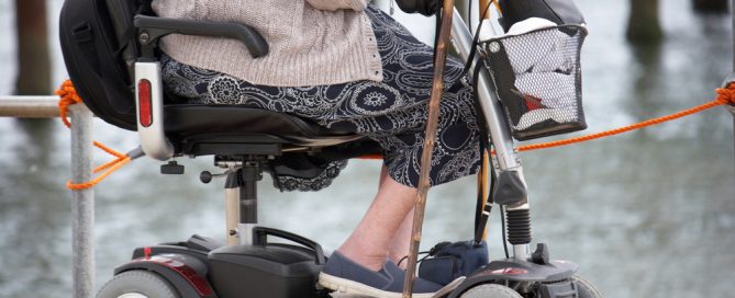 Mobility Scooter With A Person Sitting Near Water, Equipped For Outdoor Travel.