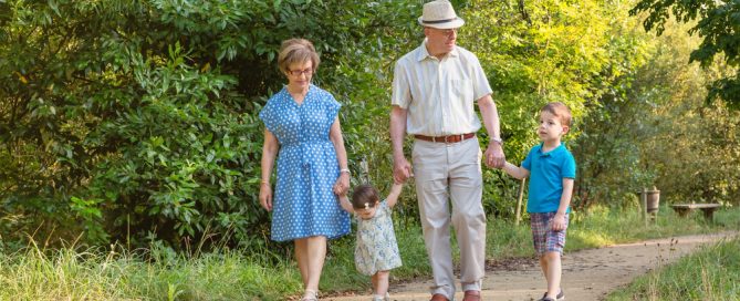 Family Walking On A Nature Trail With Young Children And Elderly Grandparents.