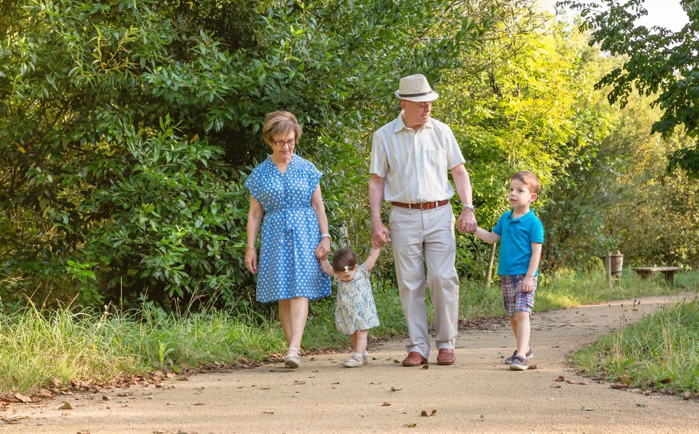 Family walking on a nature trail with young children and elderly grandparents.