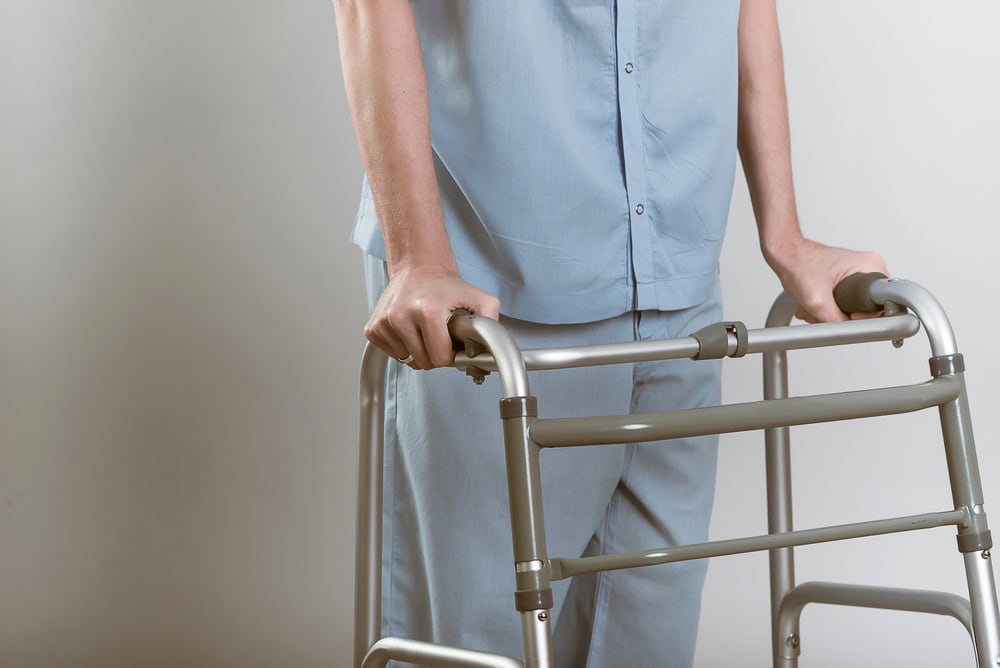 Person using a walker for mobility assistance in a healthcare setting.